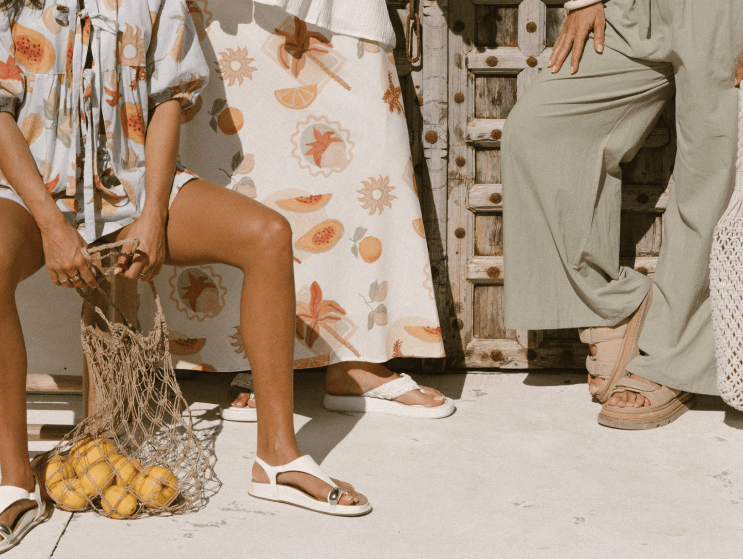 Three women wearing linen printed sets, relaxed sitting on stairs outside in a fashionable manner