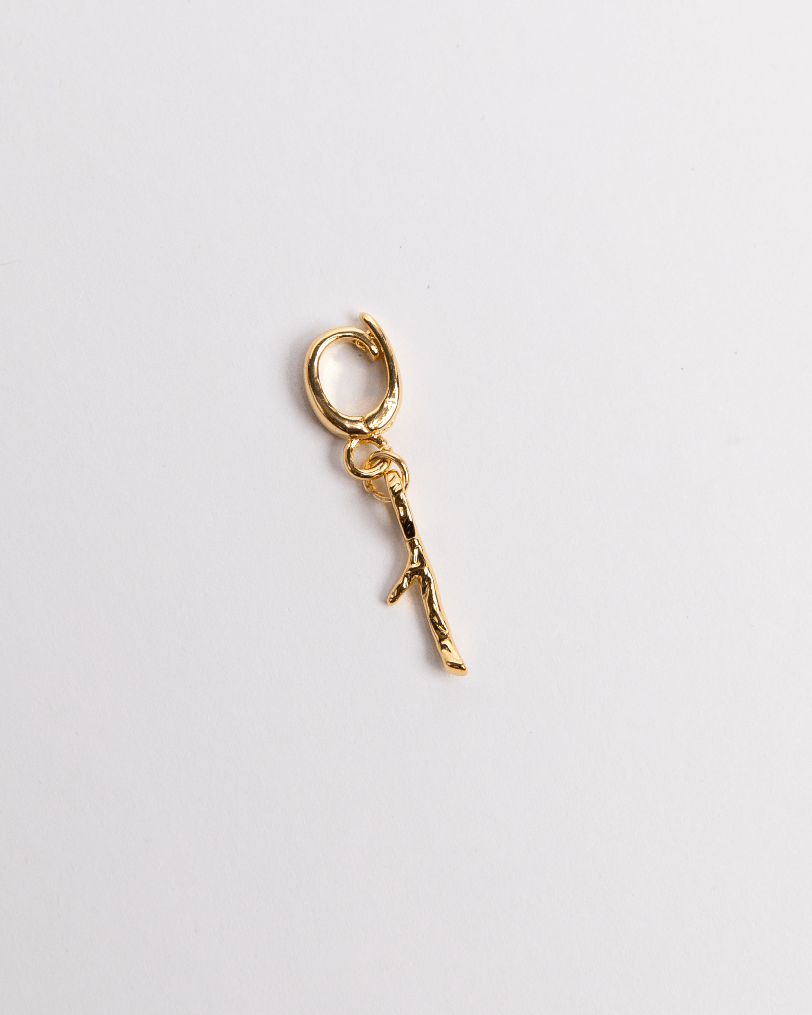A gold-colored charm with a number '1' design on it, isolated on a white background.