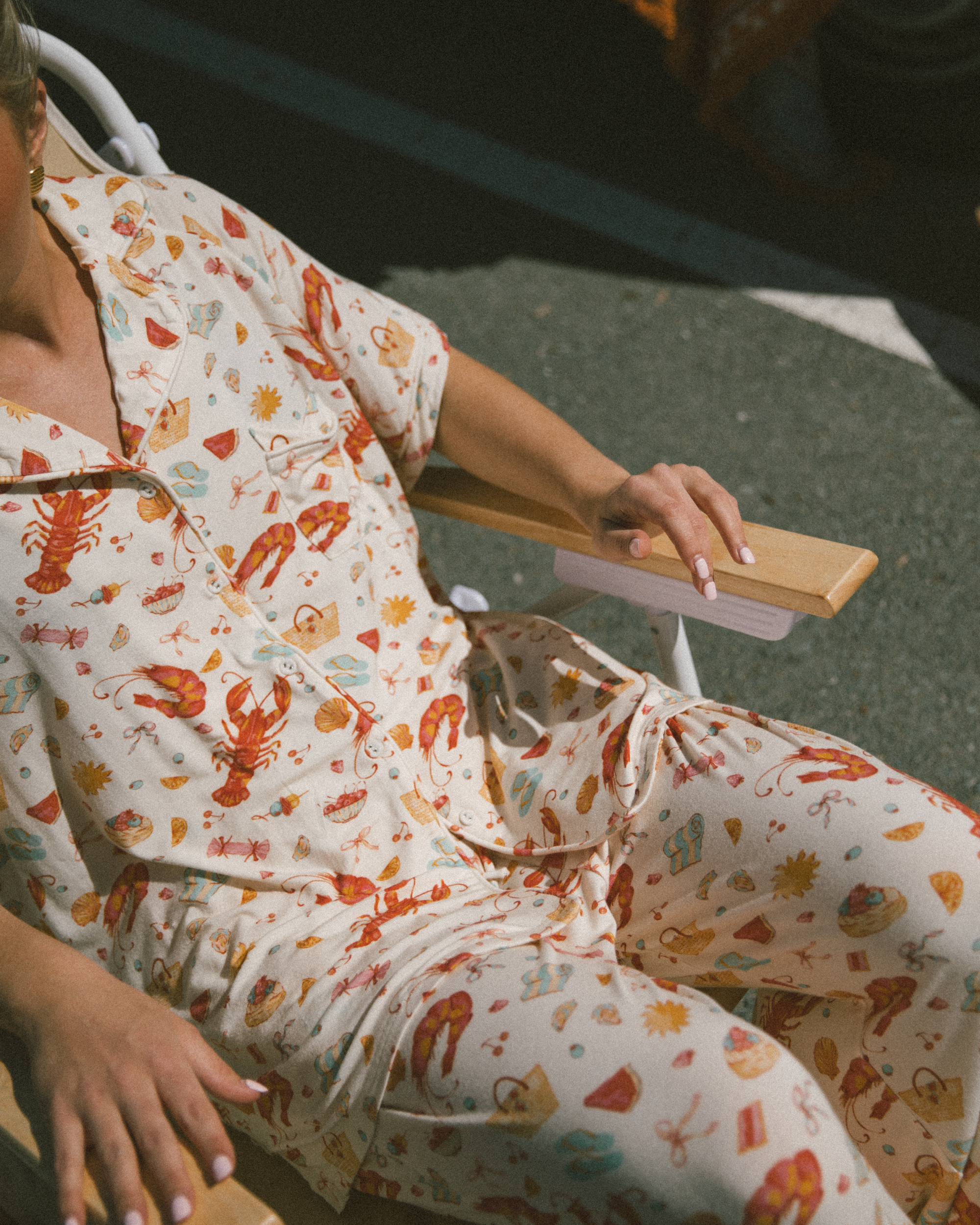 Person sitting on beach chair, wearing matching PJs in a australians pattern design.