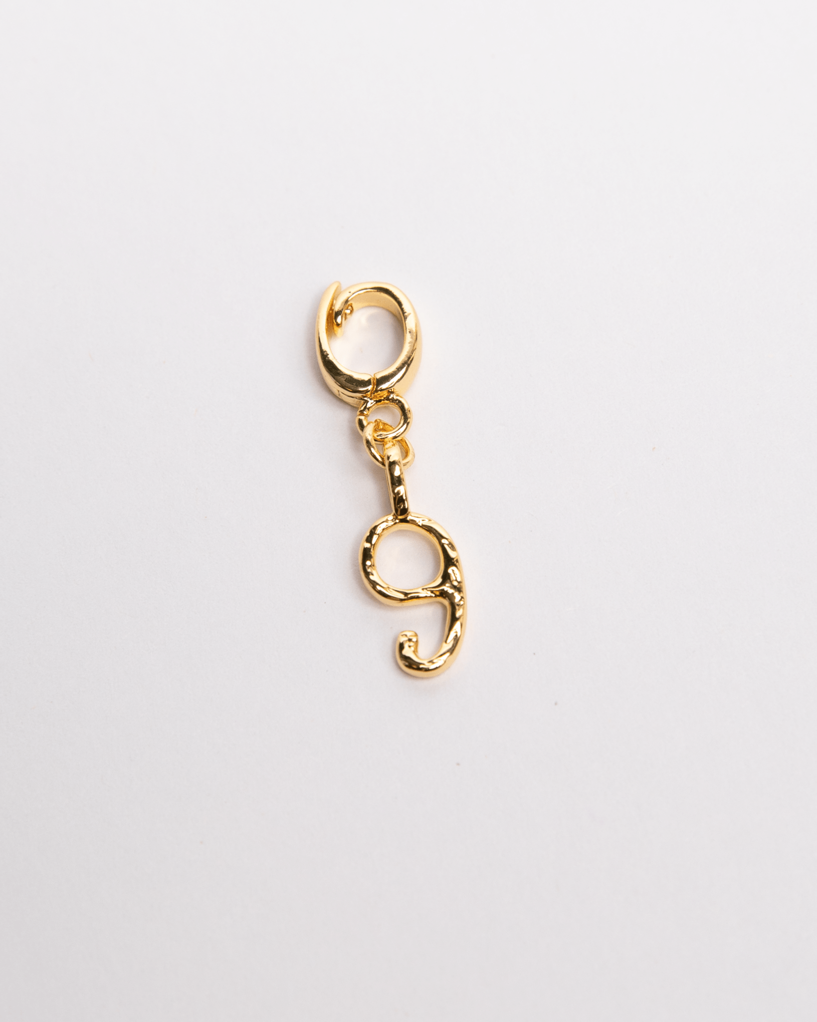 A gold-colored charm in the shape of the number 9 with a secure clasp, designed for attachment to necklaces or bracelets.
