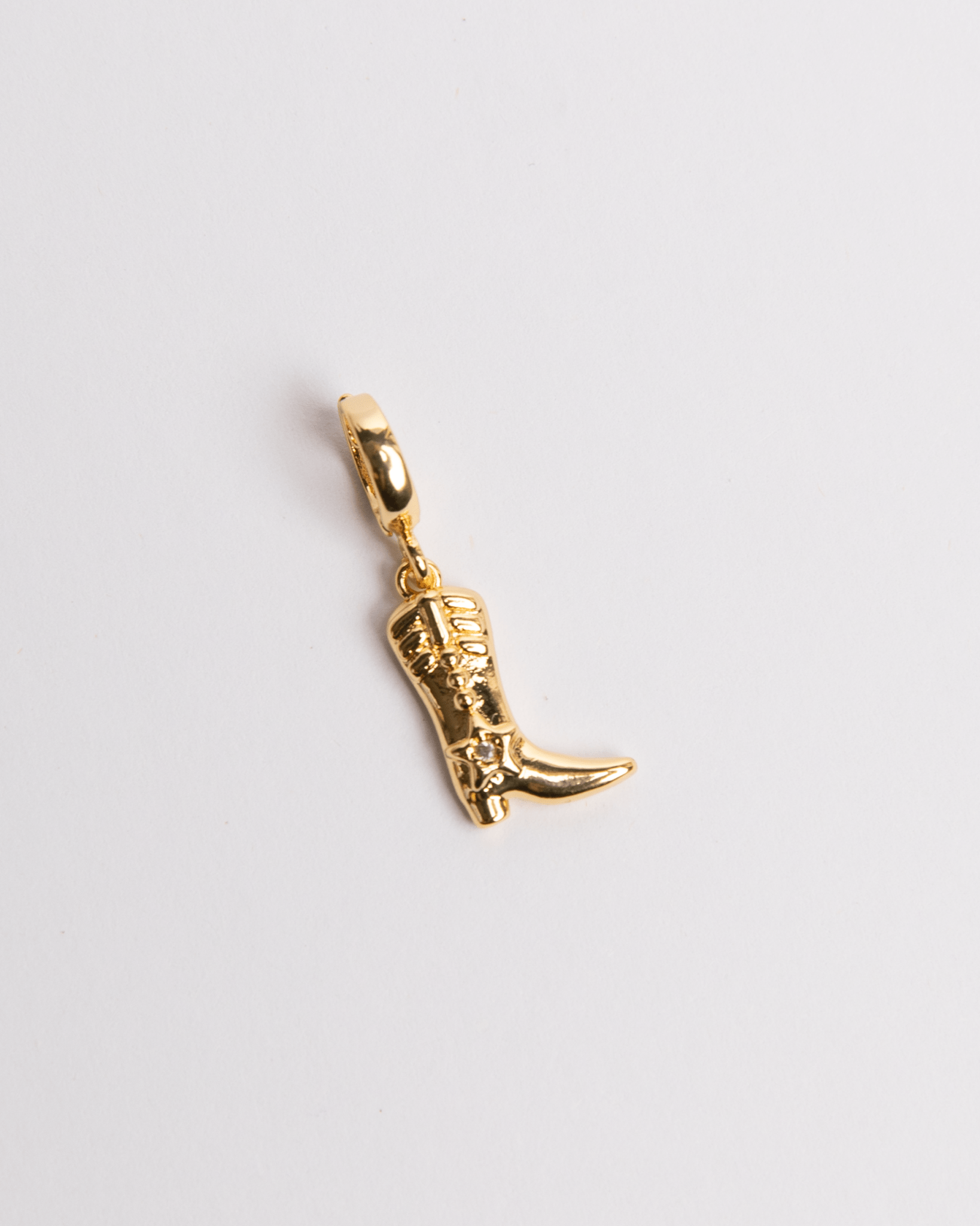 A gold-plated cowgirl boot charm against a white background.