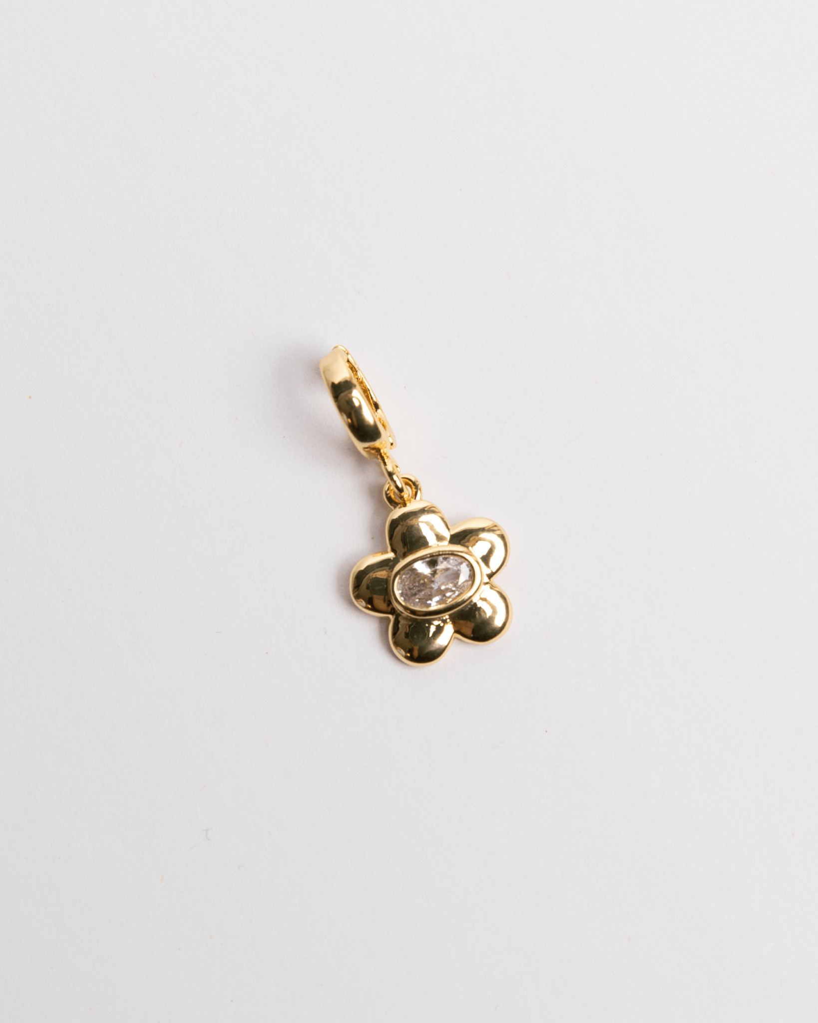 A gold-colored charm in the shape of a flower with a small diamond in the center.