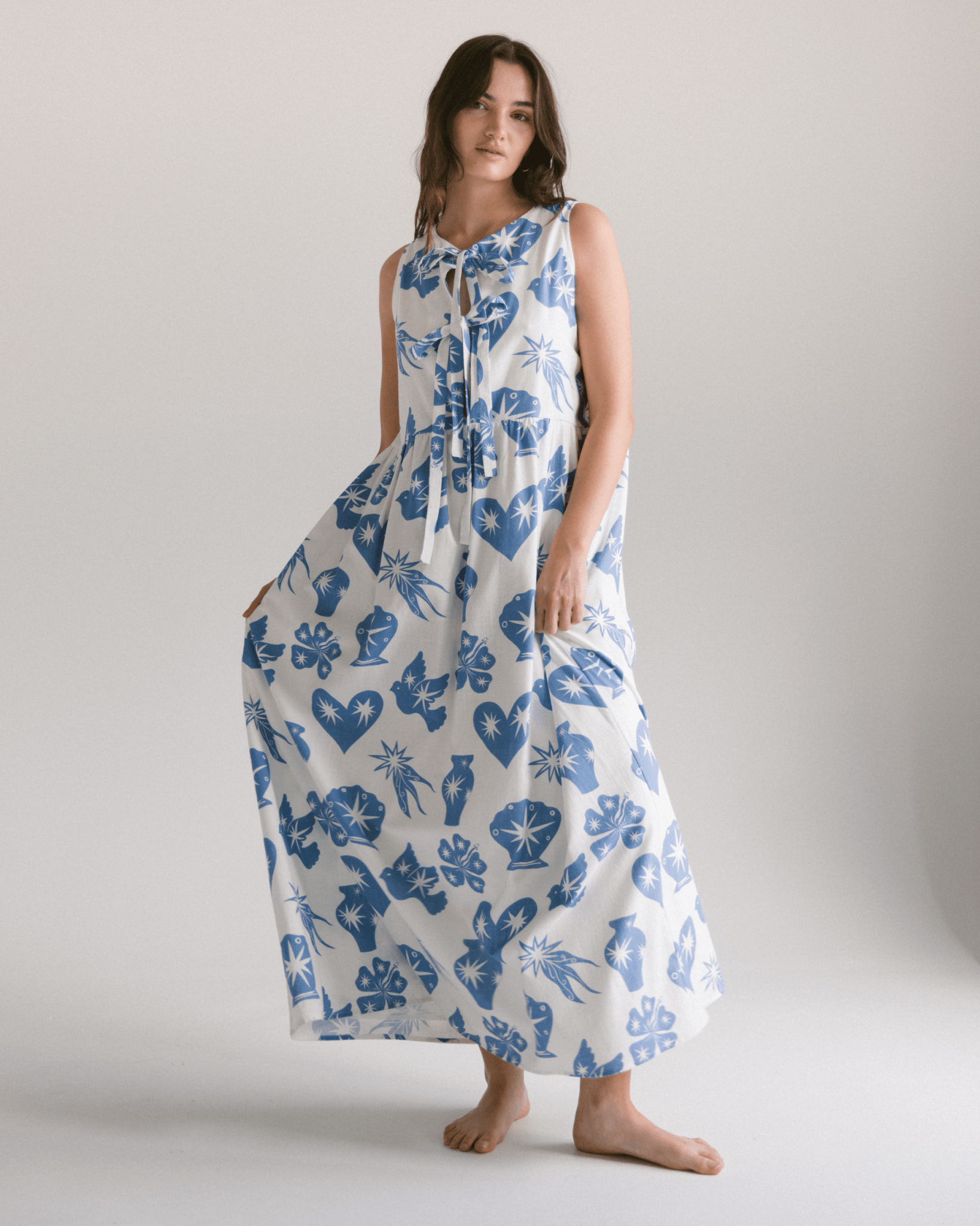 Woman wearing a long blue and white patterned dress on a plain background