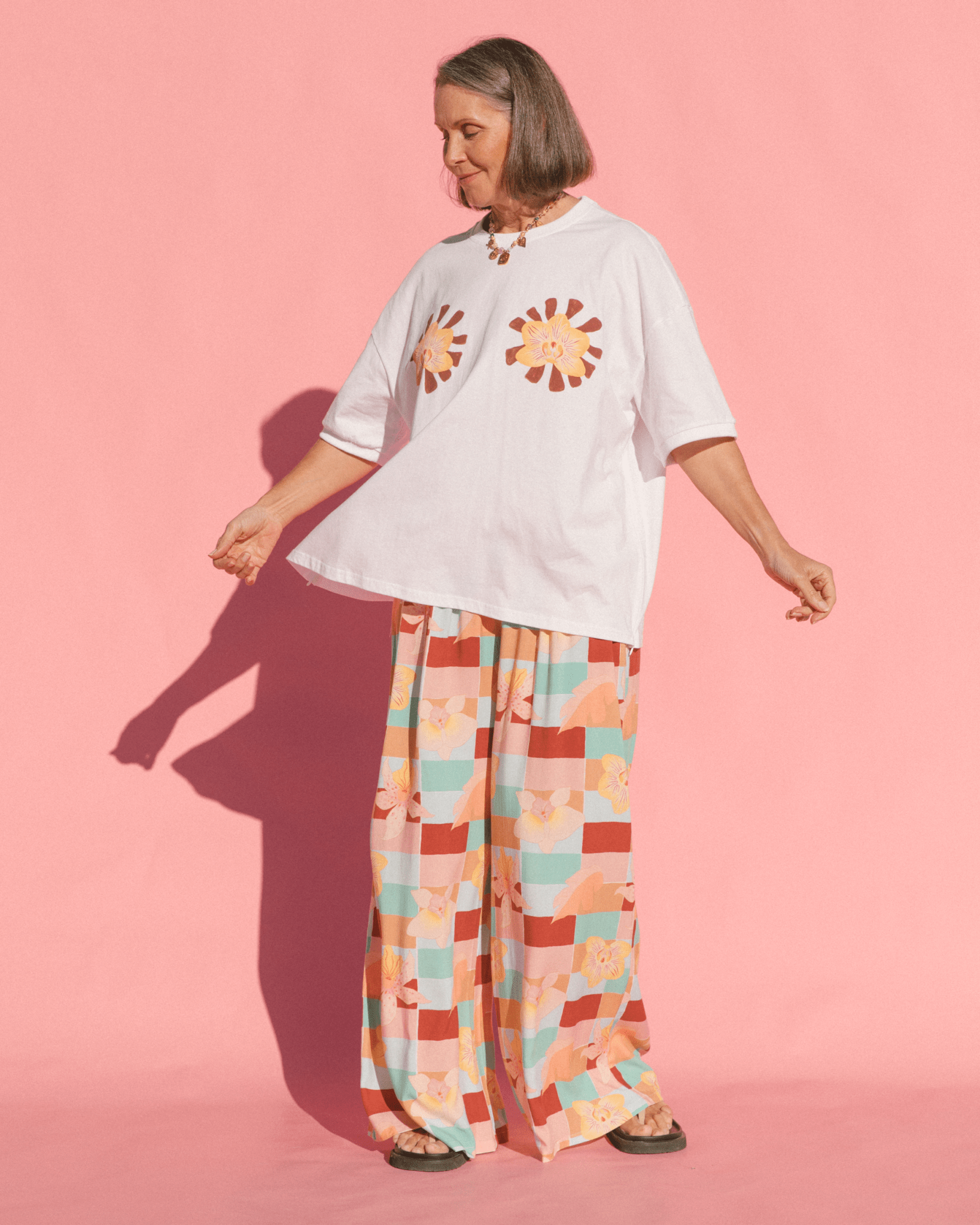 Woman wearing white oversized maternity tshirt with checkered multicoloured pants.