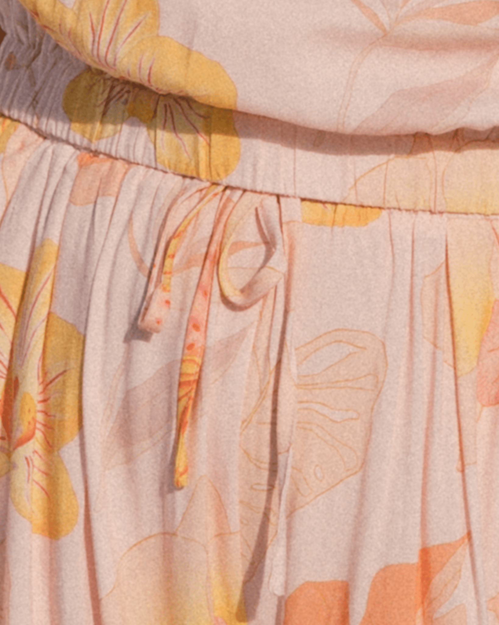 Close-up of a fabric with a floral pattern featuring orange, yellow, and beige colors.
