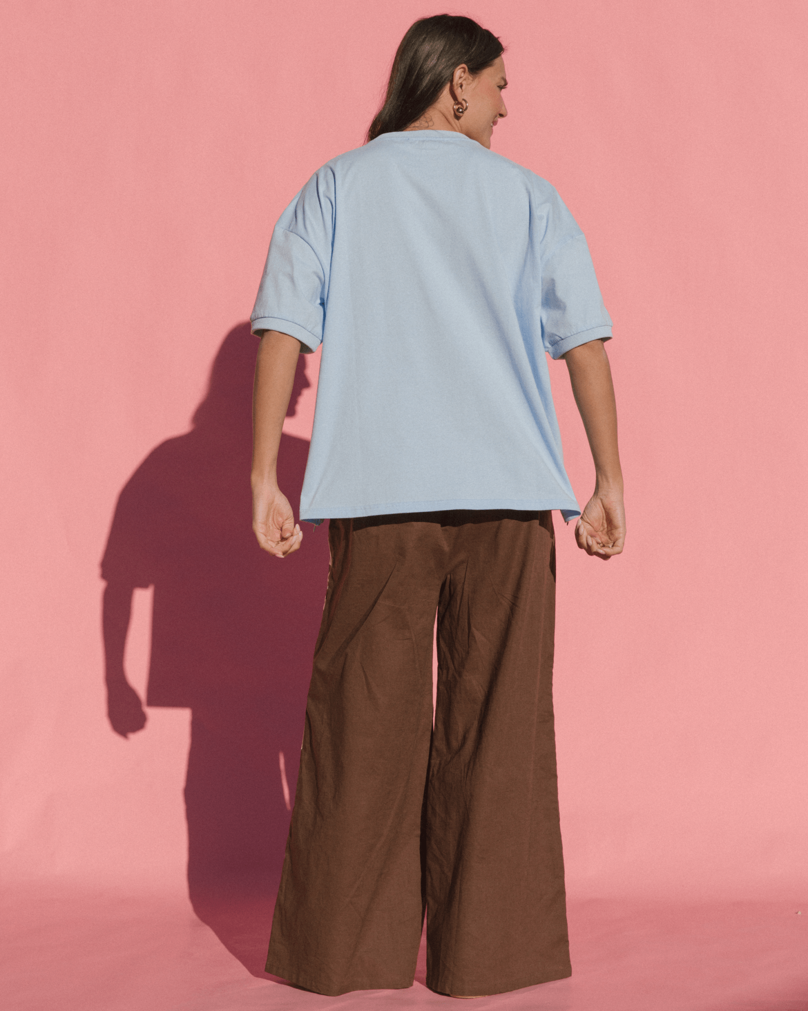 Person wearing blue oversized tshirt with drop shoulder and brown wide cotton pants.