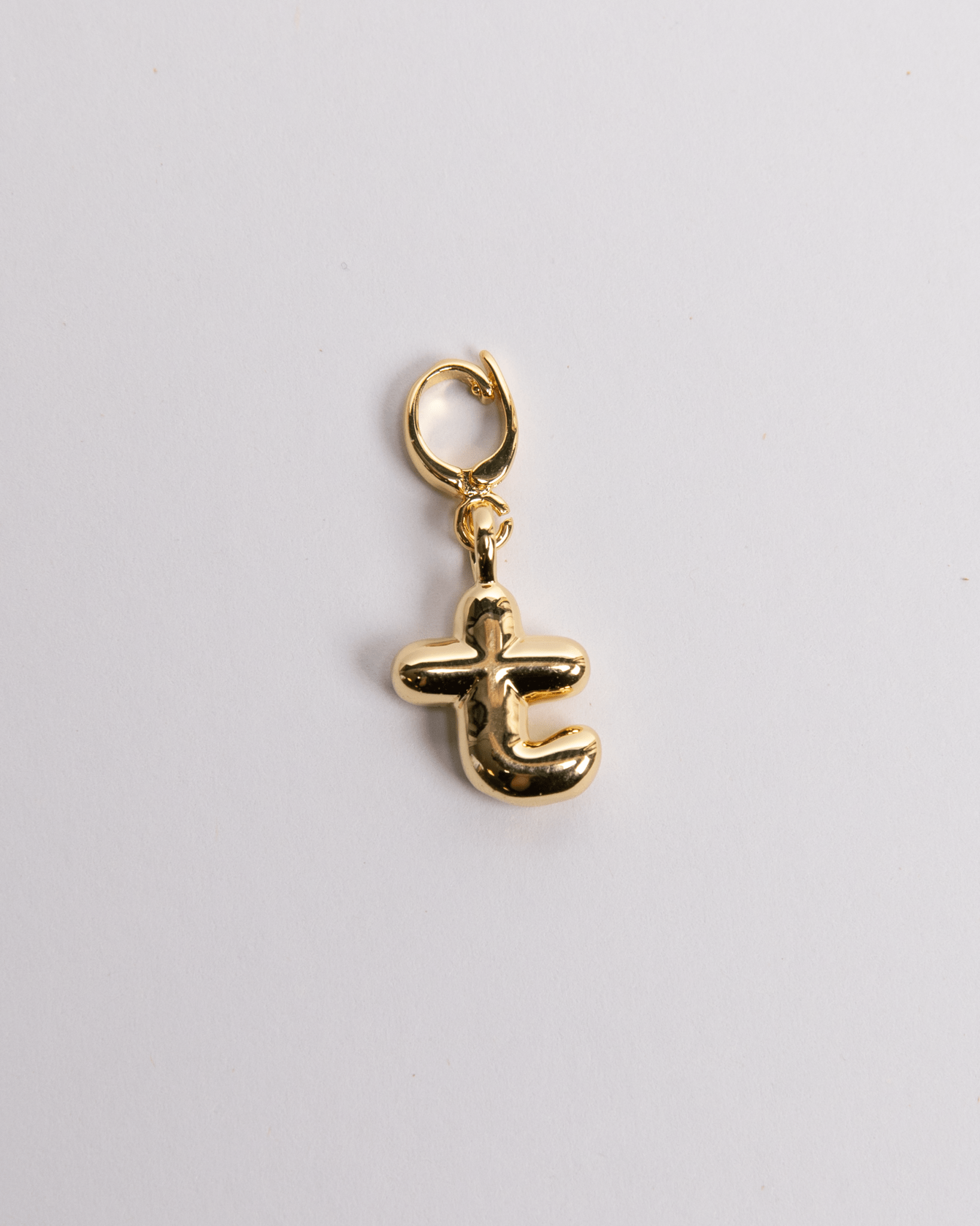 A gold-plated stainless steel charm in the shape of the letter T with a secure clasp for attachment to jewelry.