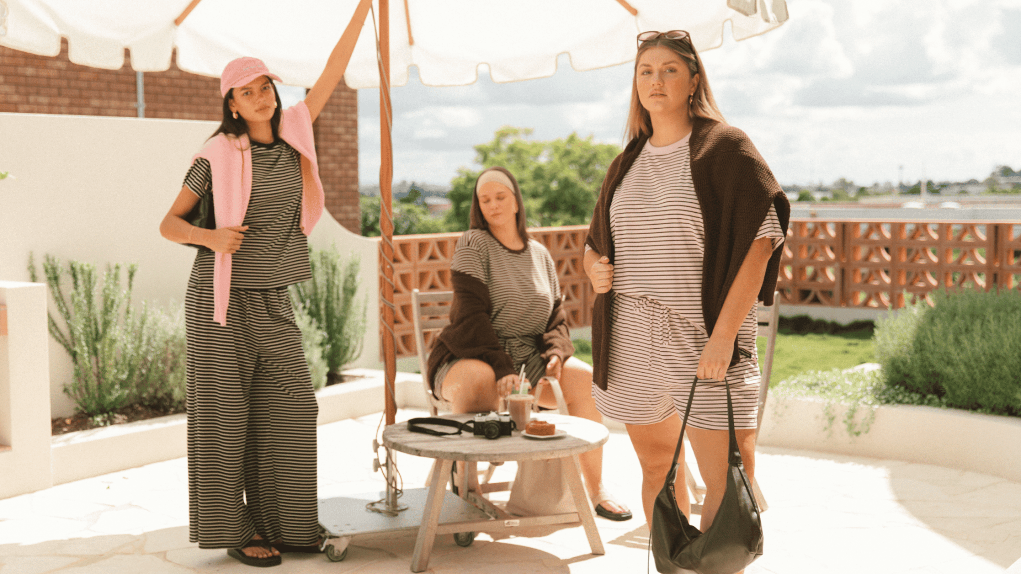 Three women wearing linen printed sets, relaxed sitting on stairs outside in a fashionable manner