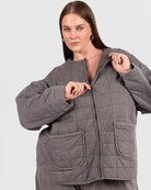 Woman wearing a warm charcoal quilted jacket with a zip and pockets. 