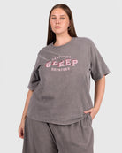 Woman wearing a gray oversized t-shirt with pink text on a white background