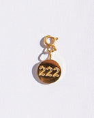 Gold circle charm with angel numbers '222' on a white background