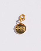 Gold circle charm with angel numbers '444' on a white background