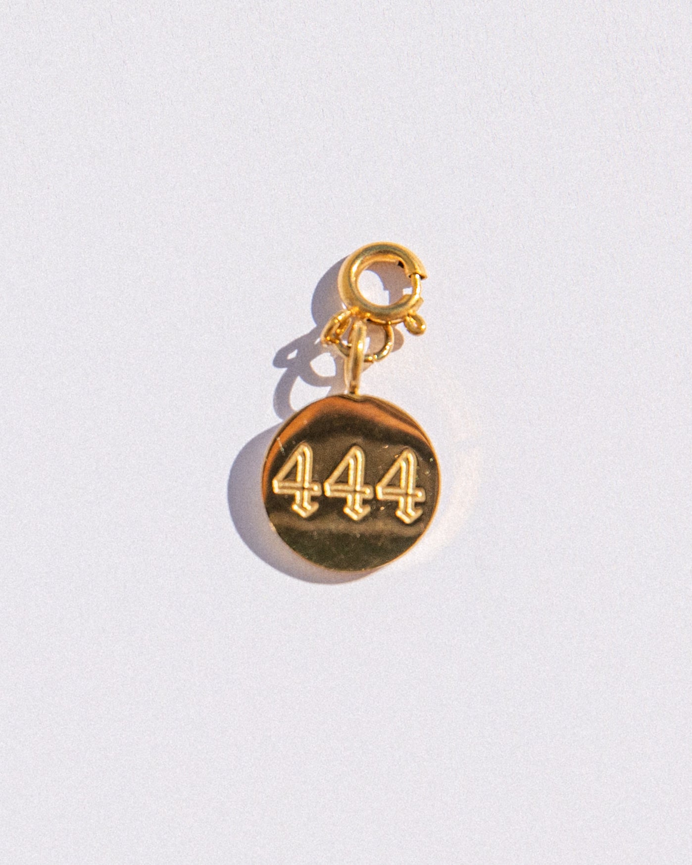 Gold circle charm with angel numbers '444' on a white background