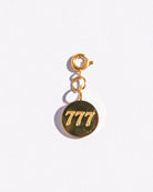 Gold circle charm with angel numbers '777' on a white background