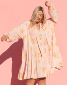 Woman wearing oversized flowy smock dress with breastfeeding access. 