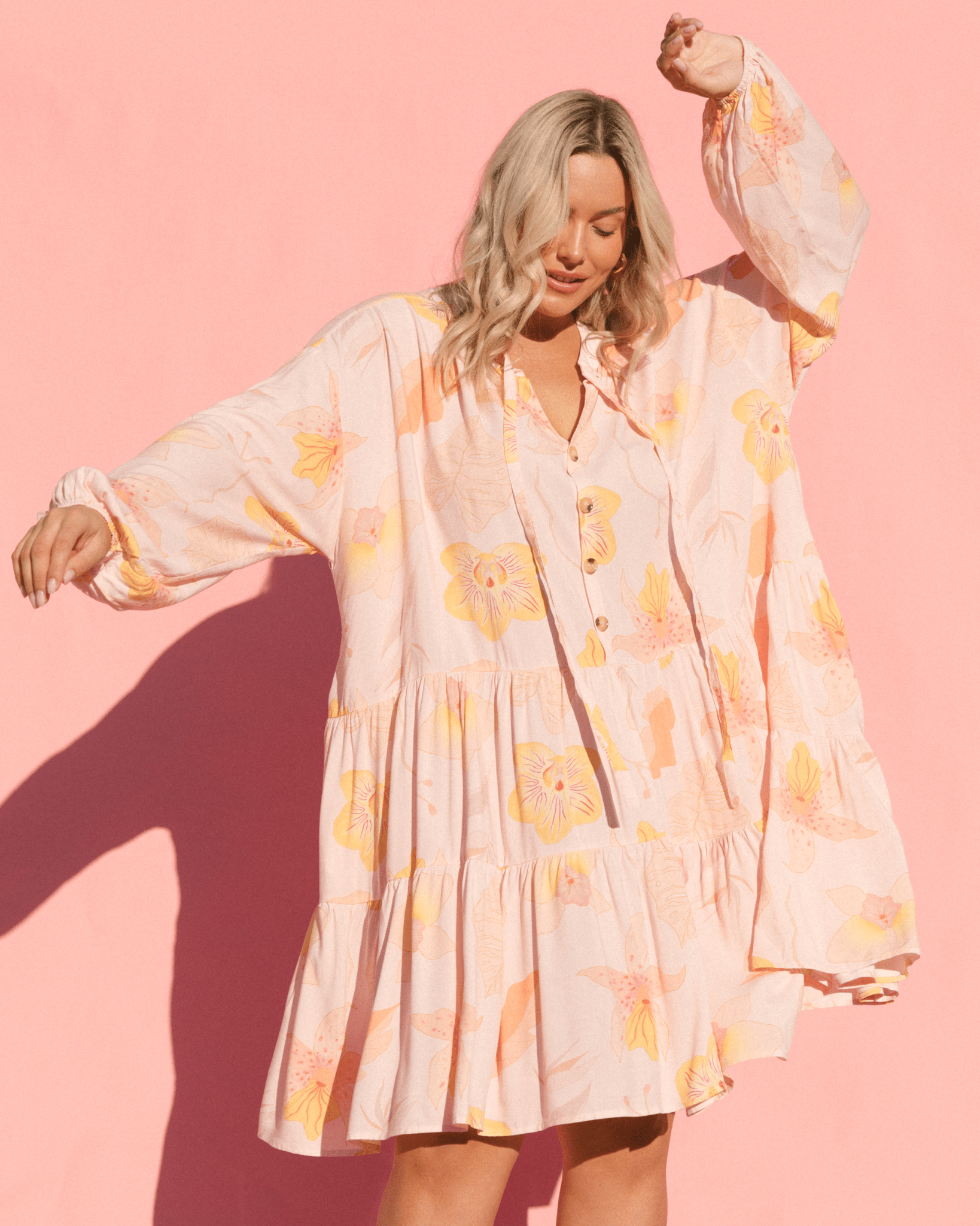 Woman wearing oversized flowy smock dress with breastfeeding access. 