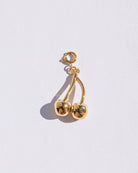 Gold cherry-shaped earring on a light gray background