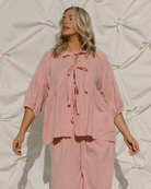 Woman wearing trendy pink tie-up top with matching long pants