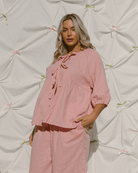 Woman wearing a pink outfit against a textured white background