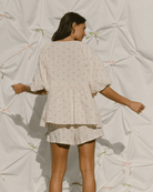 Woman wearing top & shorts set with billowing feminine sleeves and oversized style.