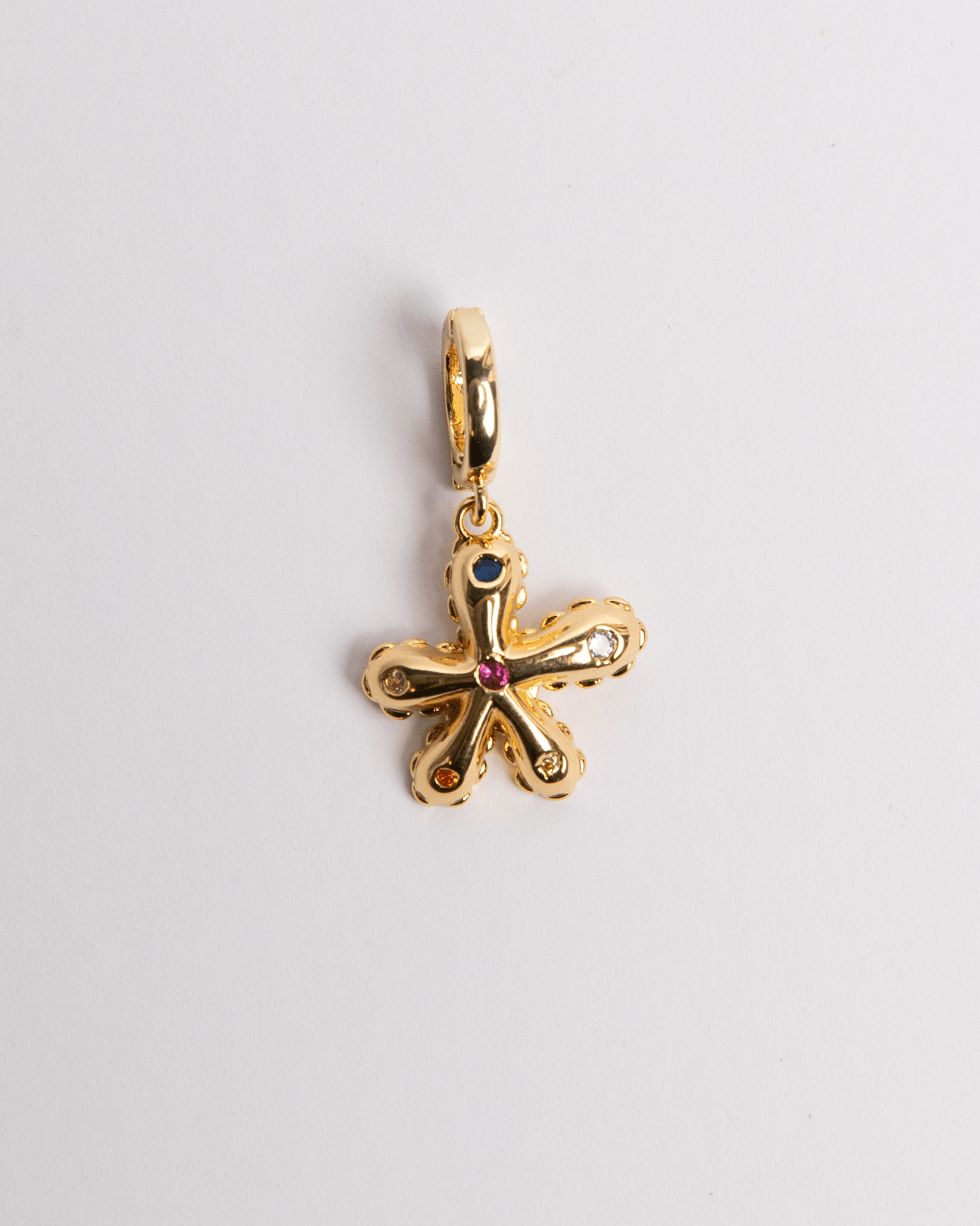 A gold-colored charm in the shape of a flower with a gemstone in the center.