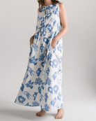 Woman wearing a long dress with blue floral pattern on a plain background