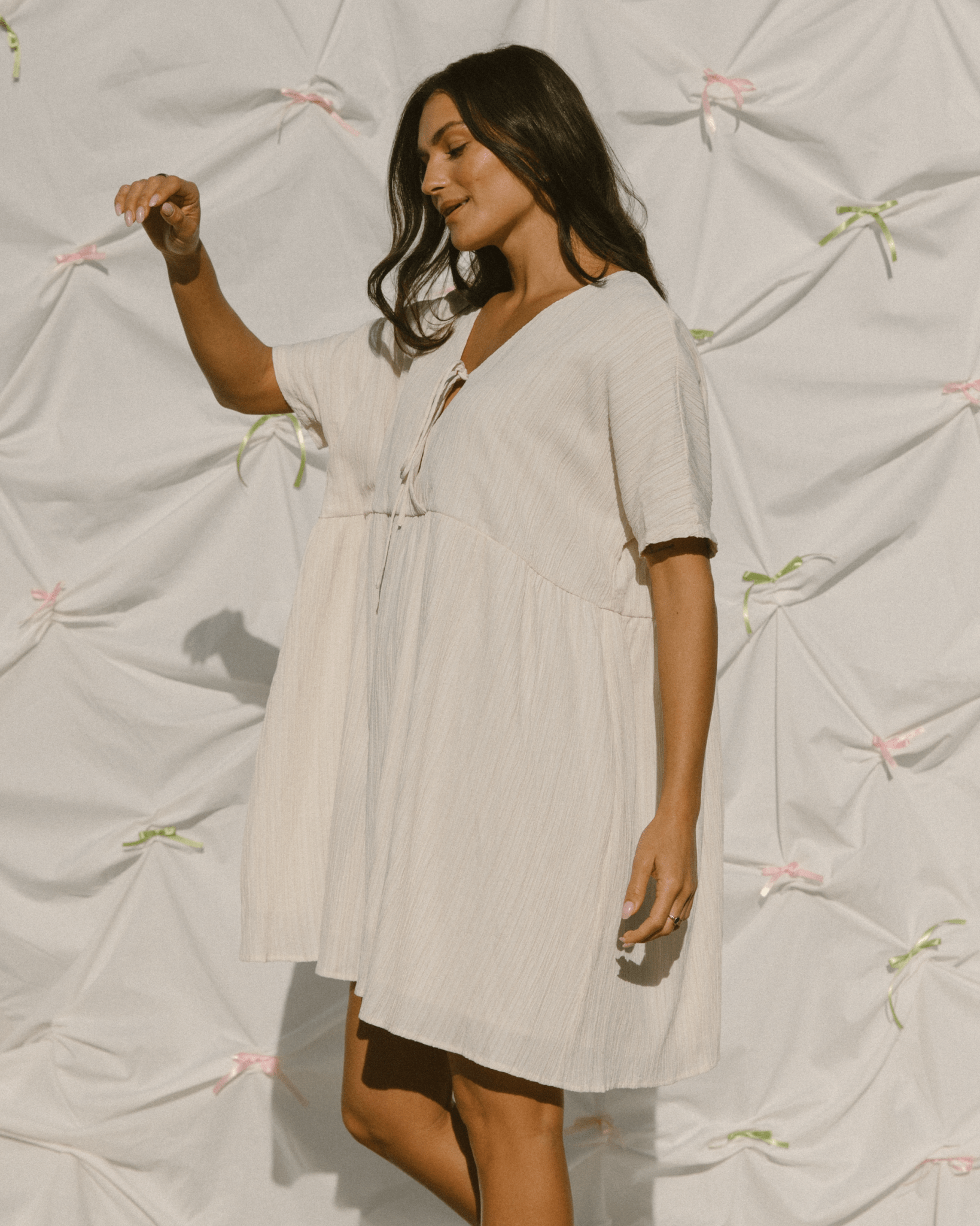 Woman wearing a light-colored dress against a textured white background