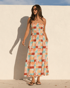 Woman wearing a colorful strapless dress against a white wall