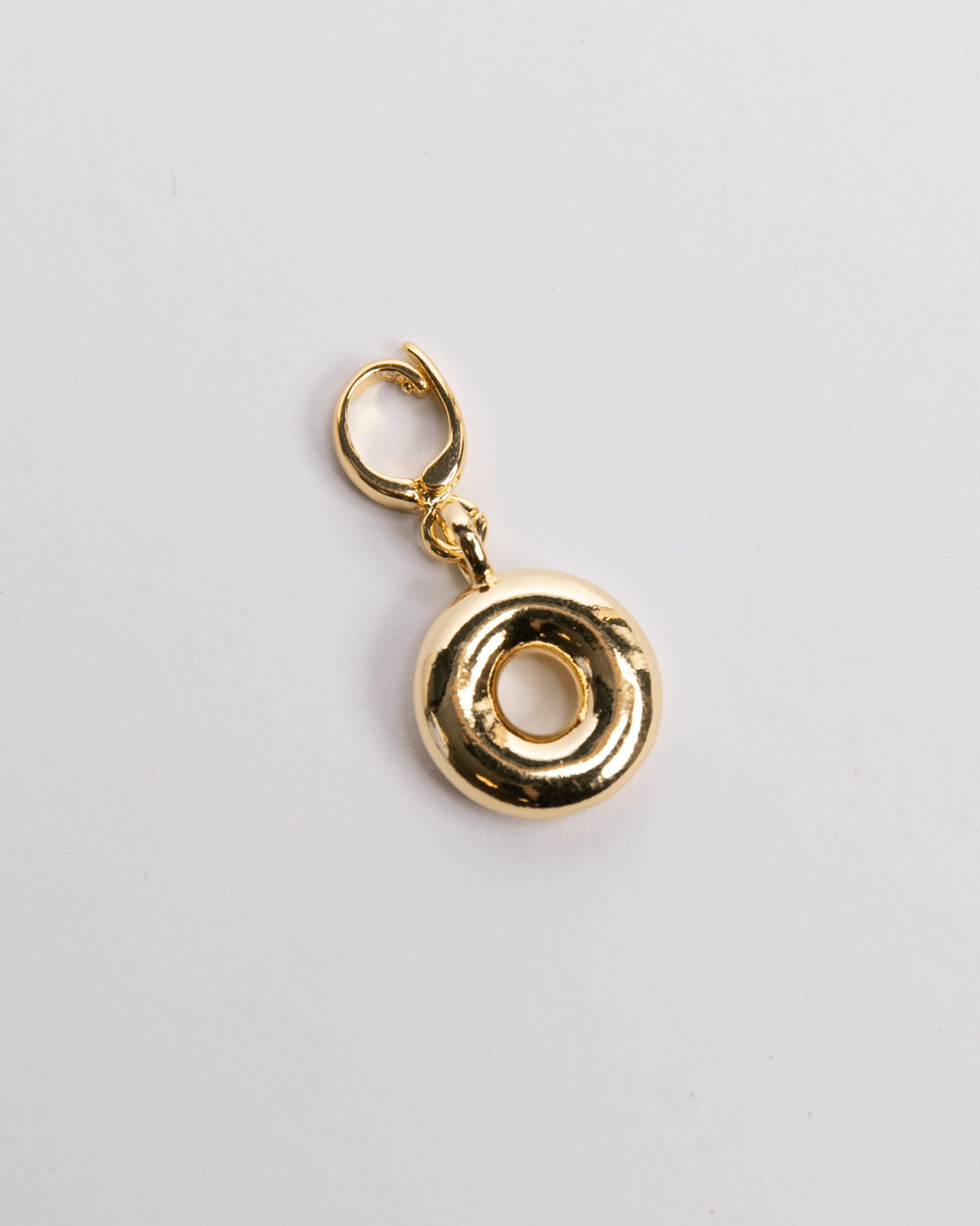 A gold-colored charm in the shape of the letter O with a secure clasp designed for attaching to necklaces or bracelets.