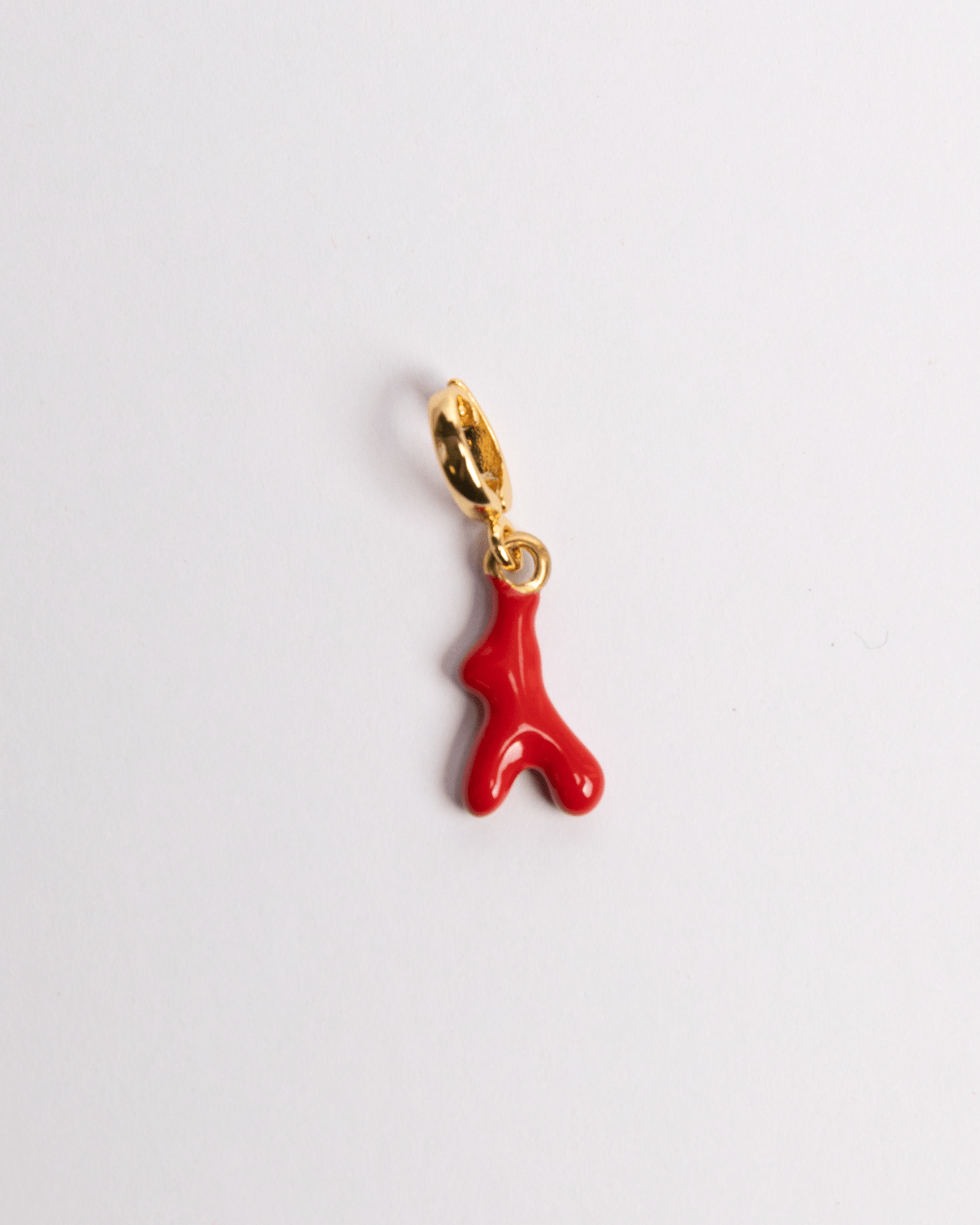 A red coral charm with a gold clasp and detailing on a white background.