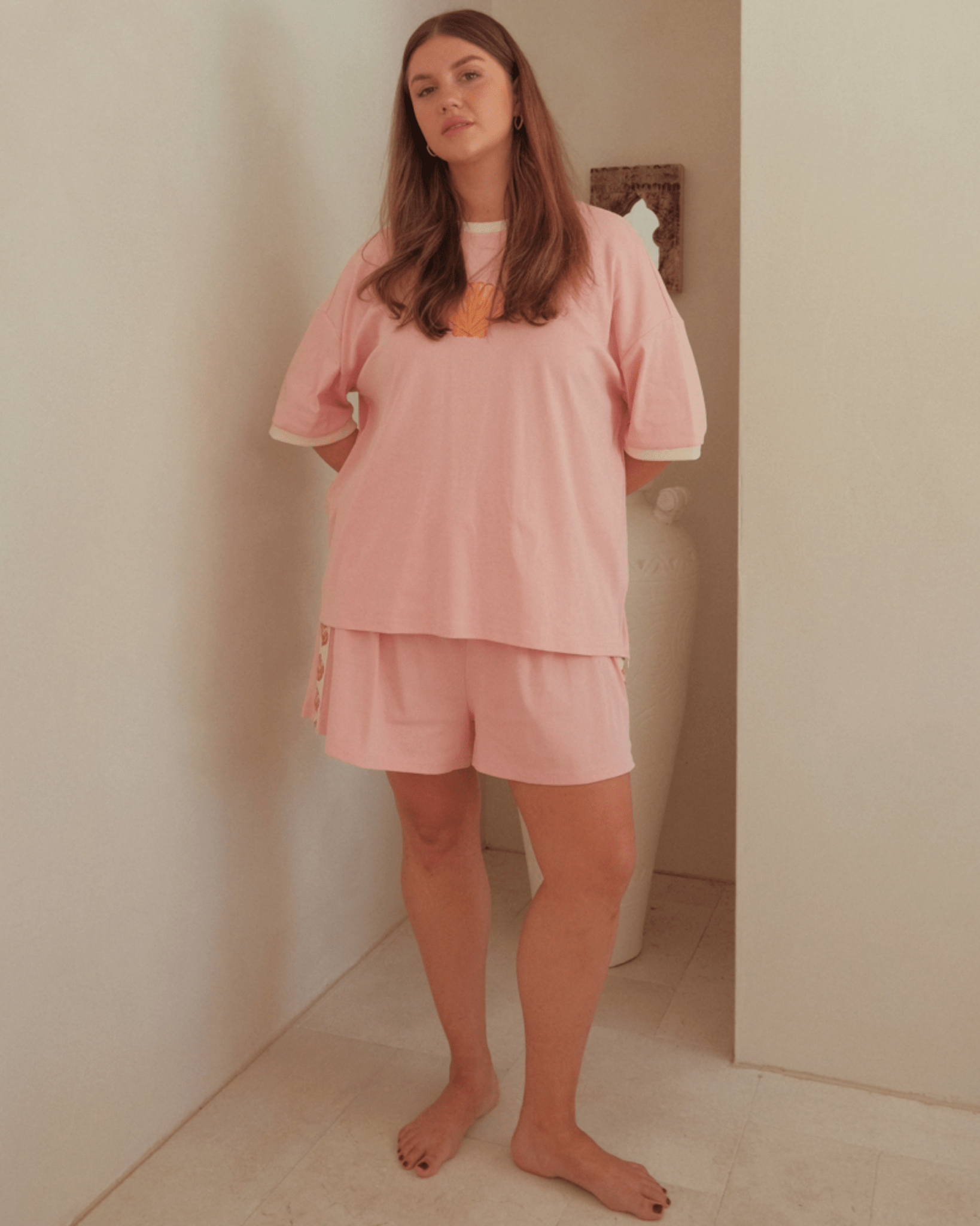 Woman wearing a pink pajama set standing in a bathroom.