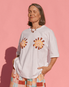 Woman wearing a white t-shirt with spring floral designs against a pink background
