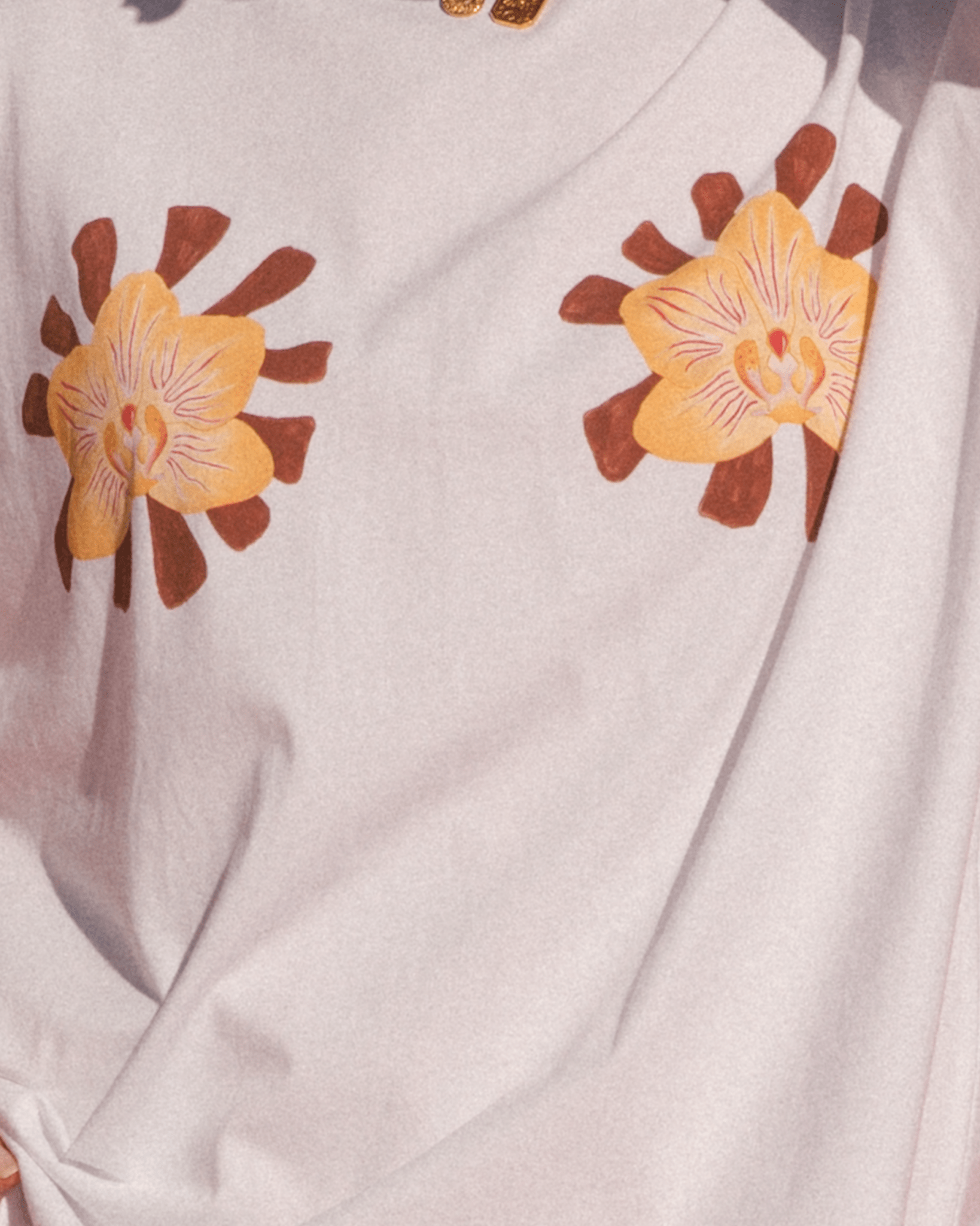 Close-up of white tee with dual orchid painted designs . 
