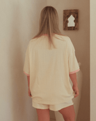 Woman wearing oversized beige loungeset with t-shirt and shorts.