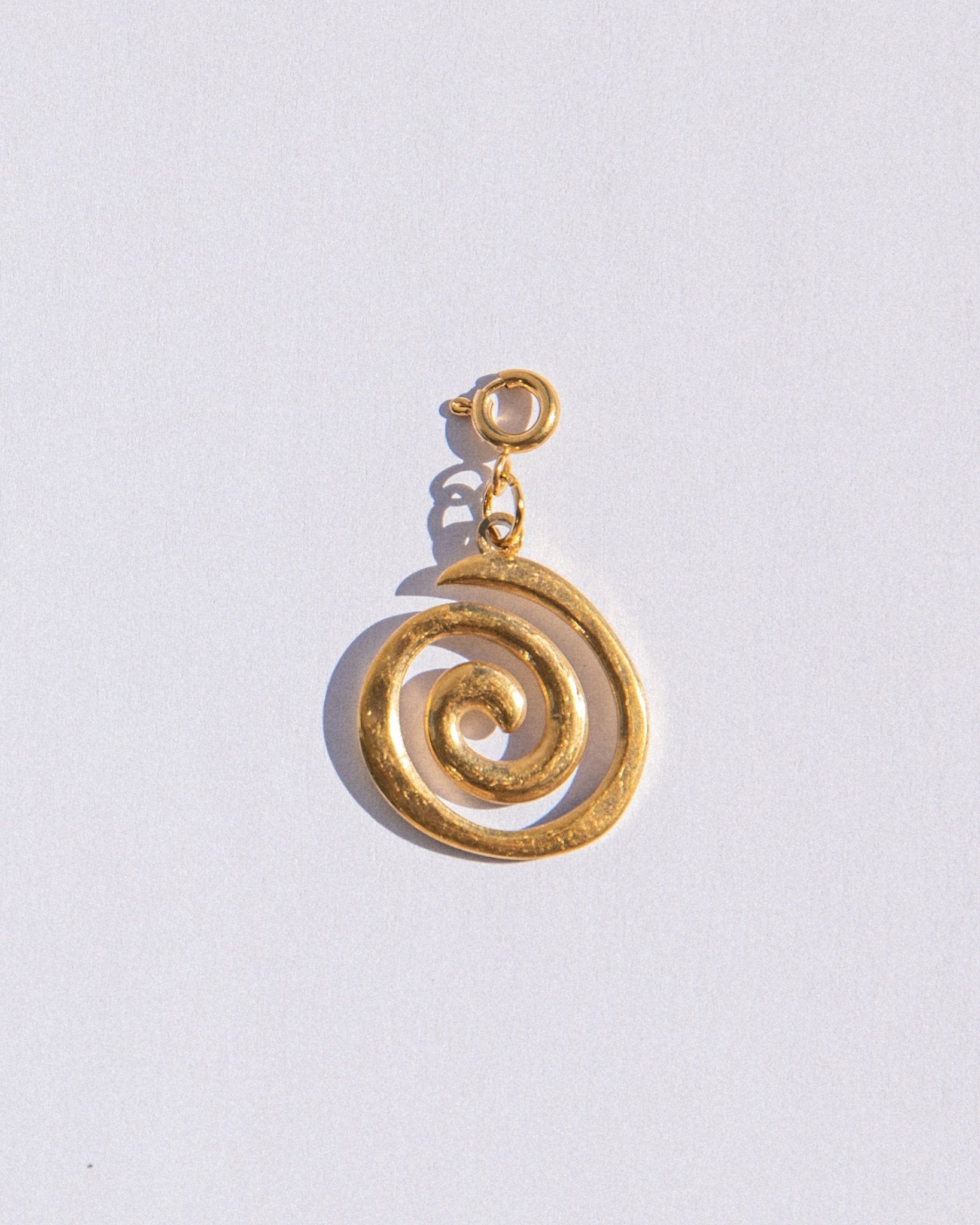 Gold spiral charm pendant on a light gray background
