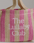 Up close detailing of embroidery of a pink & beige striped raffia tote bag. 