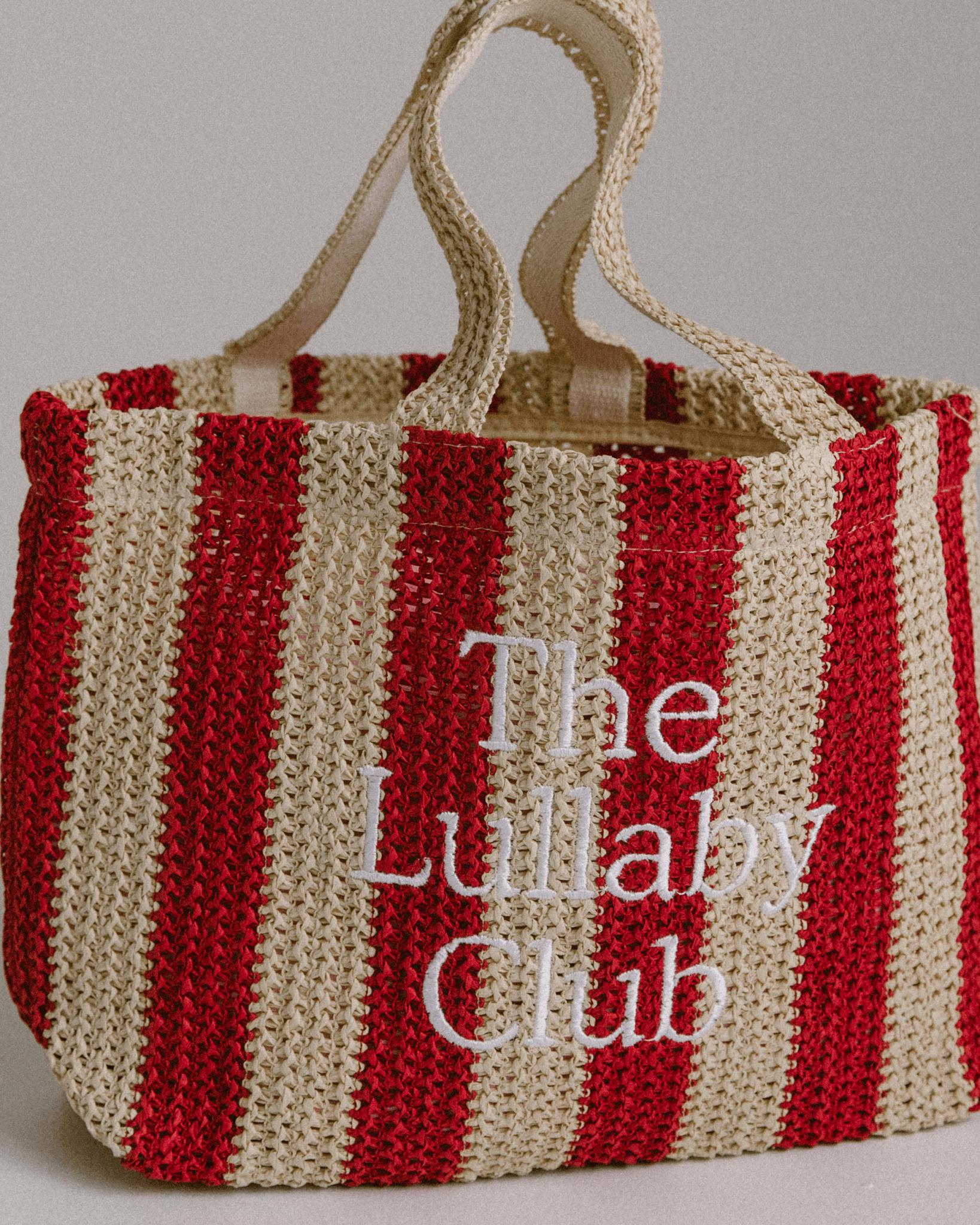 Close up of holiday style woven tote bag in red and beige stripe. 