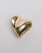 Gold heart-shaped hair accessory on a light gray background