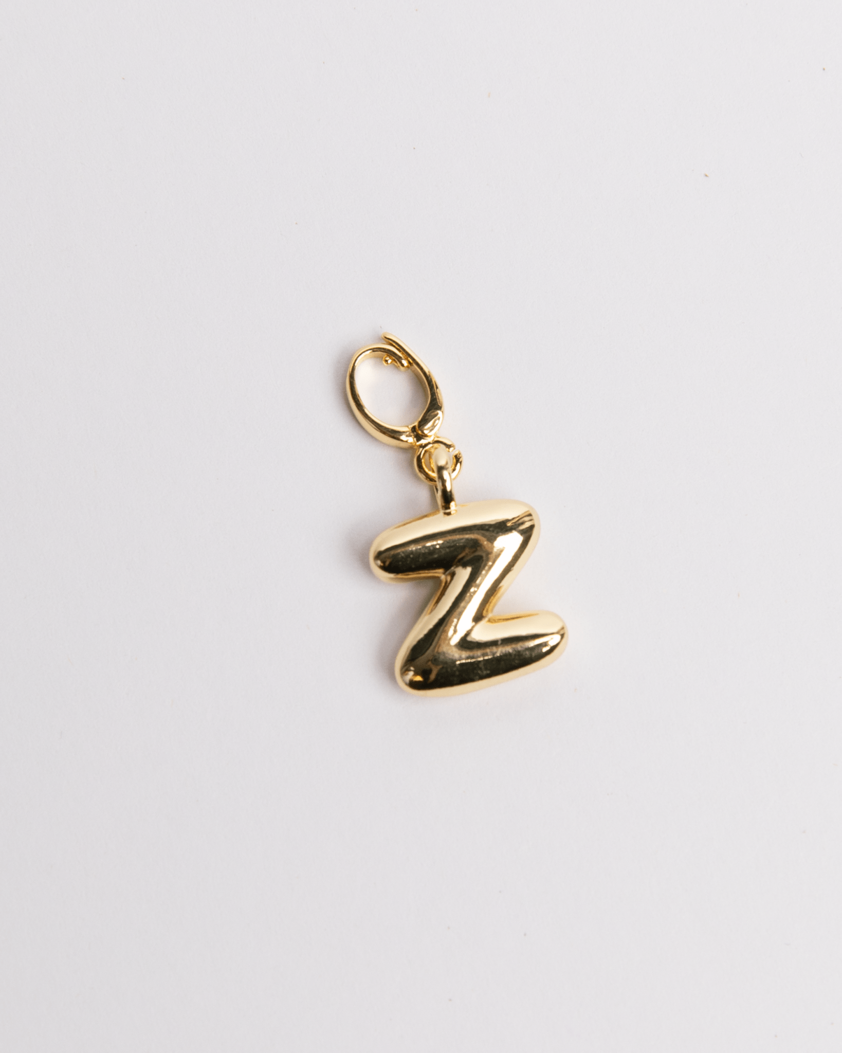 A gold-plated stainless steel charm in the shape of the letter Z in a bubble design with a secure clasp designed for attaching to necklaces or bracelets.