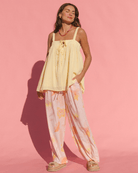 Women wearing stylish summer outfit with flowy bright yellow breathable top and lightweight floral pink long pants