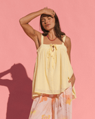 Women wearing bright yellow flowy strapless top with front tie details and matching flowy floral pink pants